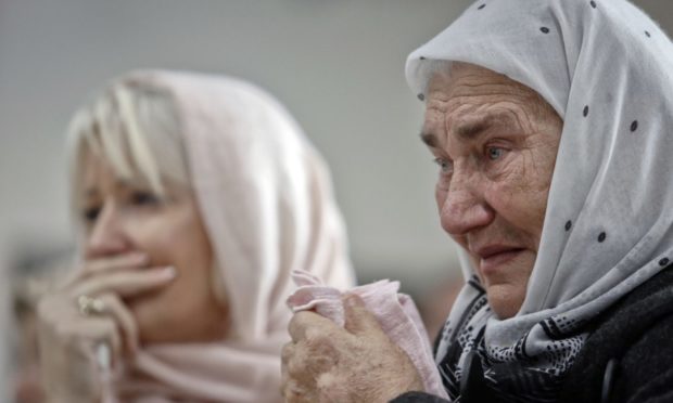 Bosnian women are overwhelmed by emotion watching the final moments of former Bosnian Serb military chief Gen. Ratko Mladic's trial at the memorial center in Potocari, near Srebrenica, Bosnia, in 2017