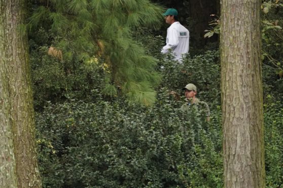 Rory McIlroycaddie Harry Diamond look for his ball in the bushes on the 13th hole.
