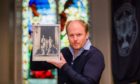Auctioneer Nick Burns holding a signed portrait of the Royal Family in 1937 showing King George VI, Queen Elizabeth, Princesses Elizabeth and Margaret.