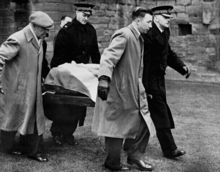 black and white photo shows police officers and men in overcoats and cloth caps removing the Stone of Destiny from Arbroath Abbey in 1950.