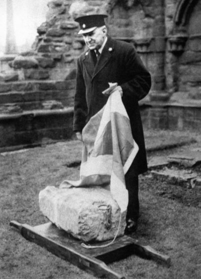 The curator of the abbey inspects the Stone of Destiny at Arbroath Abbey in 1951.