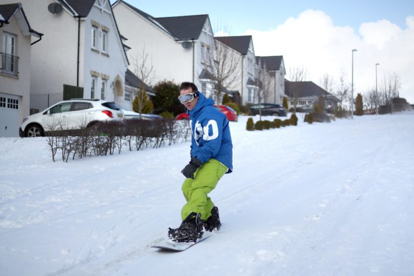 Snowboarder Kevin Trueland rides down Balmossie Road in the deep snow in Maerch 2018.
