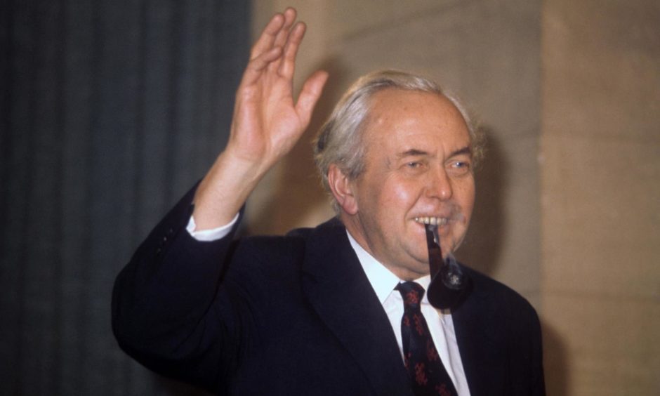 Photo shows former Prime Minister Harold Wilson waving and smoking his trademark pipe.