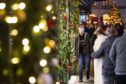 Shoppers pass Christmas light displays.