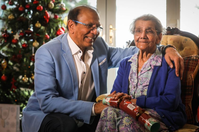 Wes Shah with his arm around his mother Daphne Shah in front of a Christmas tree