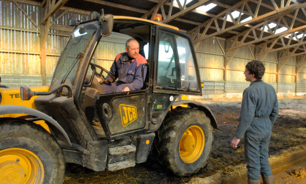 IN THE DRIVING SEAT: A farmer passes on his expertise to a young man during an agricultural apprenticeship.