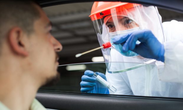 A NHS worker performing a drive-thru COVID-19 test.