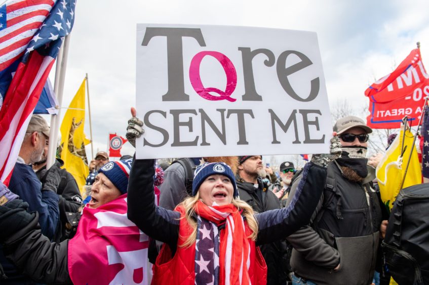 A Trump supporter holds up a "Q-Anon" sign as protesters storm the Capitol Building on January 6 2021