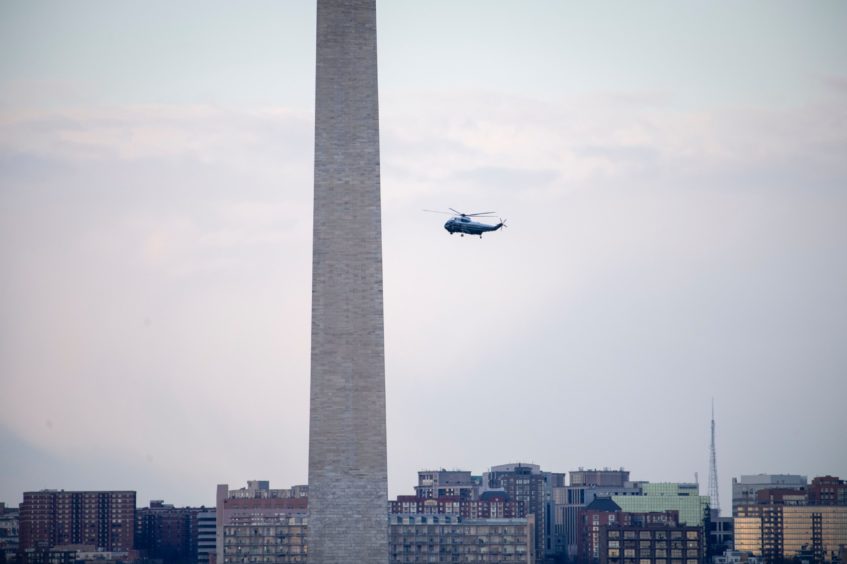 Marine One carrying President Donald Trump flies by the Washington Monument as it departs from the White House in Washington.