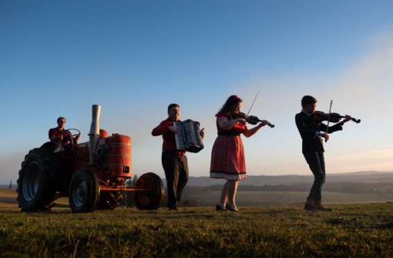 Musicians Alan Small, Gemma Donald and 10-year-old Andrew Farquharson with farmer Clark Farquharson at the wheel of 1956 Field Marshall tractor.

....Pic Paul Reid