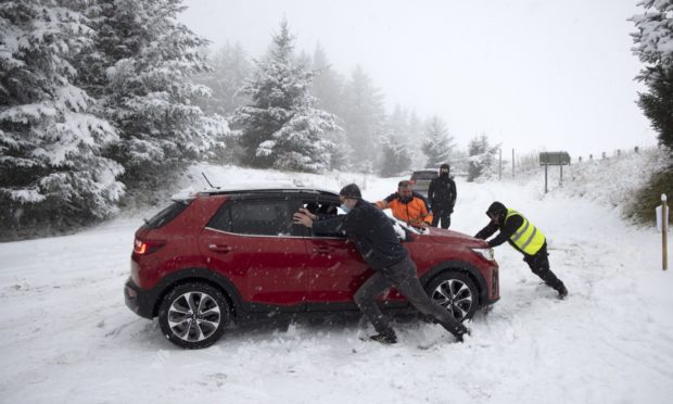 Passersby help a NHS worker stuck in the snow at the junction between the A9 and the road to Findo Gask.