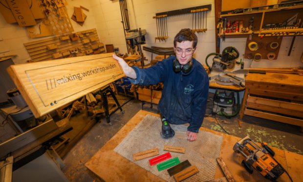 Bailey Pearce (workshop technician) with examples of the signs at The Workshop Aberfeldy.