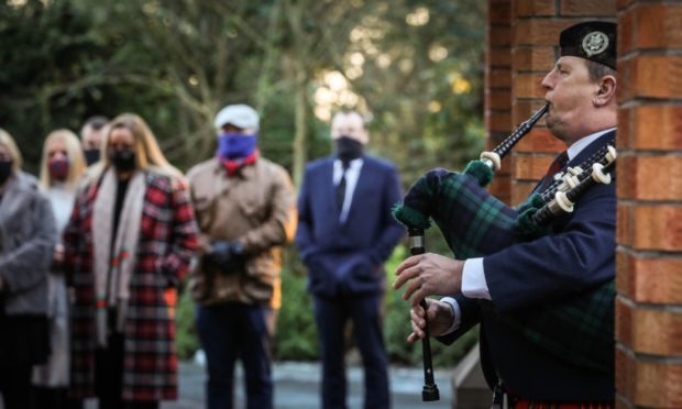 Piper Iain Bryson with mourners at the funeral.