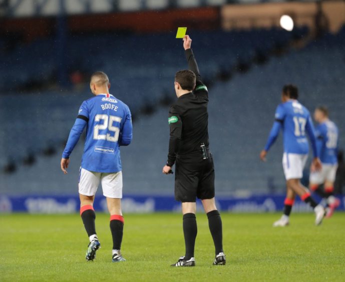 David Munro shows Kemar Roofe a yellow card.