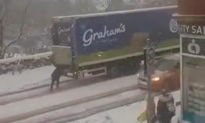 A woman appears to be 'pushing' a lorry up a snow-covered hill in Cowdenbeath. 