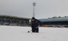 Dundee assistant groundsman Brian Robertson Jnr battles through the snow at Dens Park