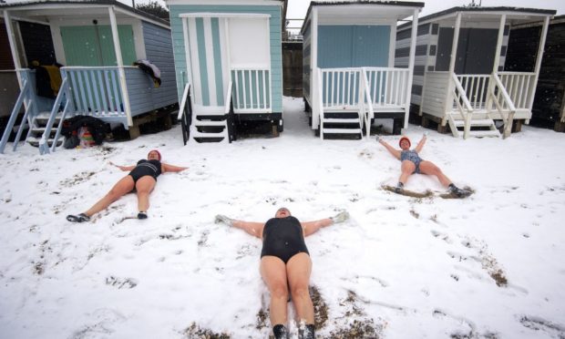 Swimmers Sallyann Manthorp, Peta Hunter and Victoria Carlin make snow angels on the beach after swimming in the 1.4 degree water at Thorpe Bay, Essex, as bitterly cold winds continue to grip much of the nation. Photo by  Victoria Jones/PA