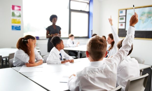 High School Students Wearing Uniform Raising Hands To Answer Question