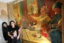 Asia Akram with her daughters Ayaana, six, and Myesha, 13, with the mural uncovered in their home.