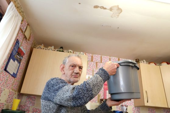 Robert Heath underneath his leaking kitchen ceiling