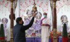 Assistant priest Deepak Shastri watches as worshiper Sudhir Jaidke rings the bell at the Hindu Mandir Glasgow after the partial easing of lockdown restrictions in Scotland allowing communal worship to resume. Picture date: Friday March 26, 2021. PA Photo. See PA story SCOTLAND Coronavirus. Photo credit should read: Andrew Milligan/PA Wire
