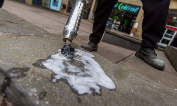 An offender cleans the pavement before the pandemic.