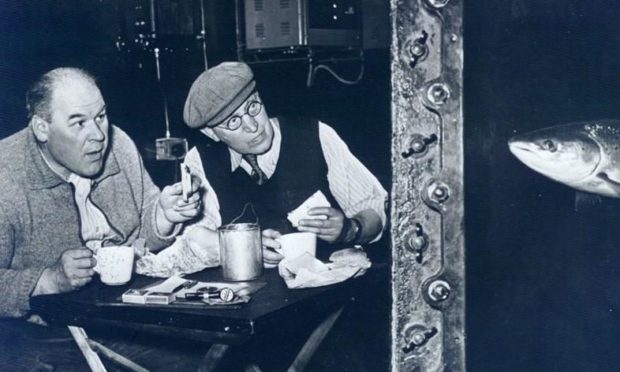 This picture, taken in the 1950s, shows Sandy Philips, left, enjoying his lunch with a colleague in the observation chamber while being spied on by a salmon making its way up the ladder
