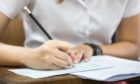 soft focus.high school or university student holding pencil writing on paper answer sheet.sitting on lecture chair taking final exam attending in examination room or classroom.student in uniform; Shutterstock ID 795333934