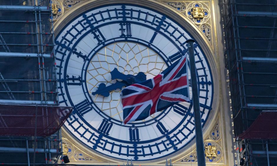 Union flag flying in front of Big Ben clock face.