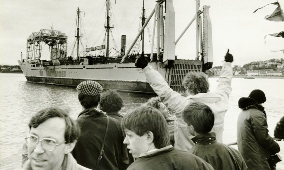 crowds cheer as the Discovery is sailed in to Dundee aboard a cargo vessel.