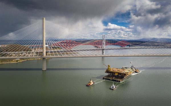 The Iron Lady barge with its cargo of a topside drilling platform for decommissioning being towed by Forth Ports tugs at the Forth Bridges into The Port of Rosyth. Airbourne Lens