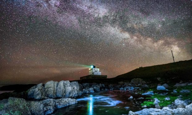 The core of the Milky Way becomes visible in the early hours of Tuesday morning as it moves over Bamburgh Lighthouse at stag Rock in Northumberland