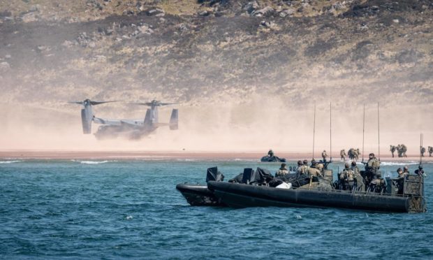 A Bell Boeing V-22 Osprey flying beside a Marines landing group.