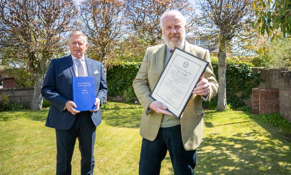 Former club president, Robert Dunn and club president, Clive Murray are seen with the Founder Members Book of Minutes and the club's charter certificate which was presented in 1922.