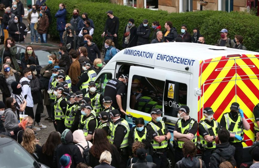 Police enter an immigration van in Kenmure Street, Glasgow which is surrounded by protesters. Picture date: Thursday May 13, 2021. PA Photo. Police were called to the Glasgow street where it is understood protesters were trying to prevent immigration officers from removing people from a property. See PA story POLICE Kenmure. Photo credit should read: Andrew Milligan/PA Wire