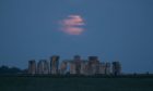 The Flower supermoon sets behind Stonehenge in Wiltshire. Picture date: Wednesday May 26, 2021. PA Photo. Being only 357,462 km away from Earth, the Moon will appear a whole 30 per cent brighter and 14 per cent larger than some previous full Moons.  Photo credit should read: Andrew Matthews/PA Wire