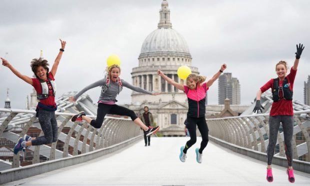 A group of friends (L-R) Marissa OMalia, McKenzie Webster, Kelly Willis and Bjorg Fridbjornsdottir jump for joy to celebrate McKenzie's birthday on the Millennium Bridge, London, with wind and rain forecast to ravage the UK on the first Friday that people have been allowed to meet in large groups outside in England. Picture date: Friday May 21, 2021. PA Photo. See PA story WEATHER Wet. Photo credit should read: Yui Mok/PA Wire