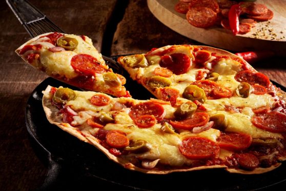 Tasty crispy oven-baked tortilla pepperoni pizza with spicy Italian sausage, melted cheese and tomato with a single slice being served in a restaurant, close up view; Shutterstock ID 503969227; 7a3cb517-0d6a-4fe0-8f79-2d2e628e0ffc