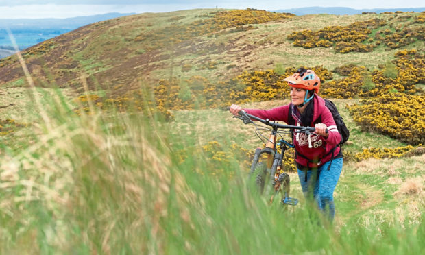 Gayle pushing her bike up a steep section of the Hill of Alyth.