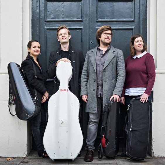 The band The Castalian Quartet posing with their instruments in front of a black door