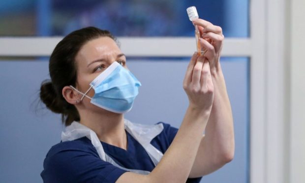 A healthcare worker fills a syringe with a dose of the Covid vaccine at a clinic