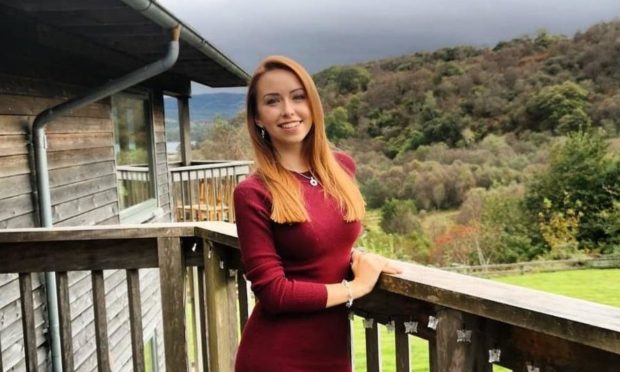 Jen Crews standing on a balcony with woodland in the background.