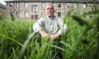Neil McLaren sits in the overgrown grass where needles have been found.