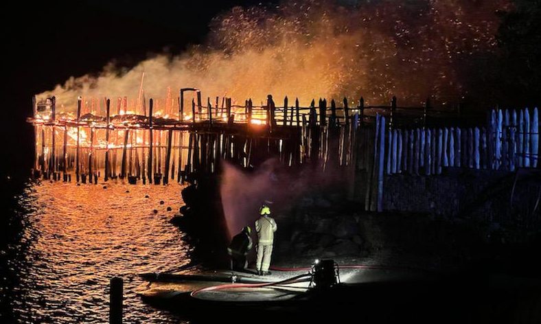Firefighters at the scene of the 2021 fire at the Scottish Crannog Centre, with flames shooting into the night sky.