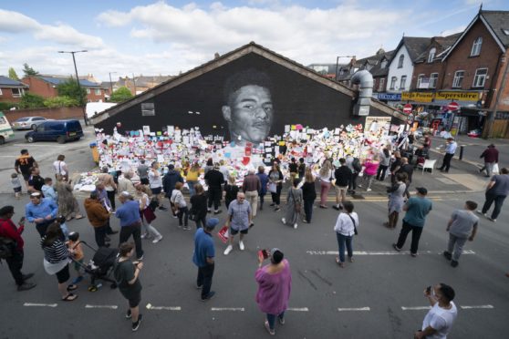 Crowds at the mural honouring footballer Marcus Rashford, where vandalism was covered up with positive messages.