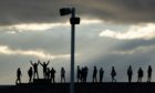 People along Irvine Harbour wall listen to music from one of the speakers on Irvine Beach, on the Ayrshire coast, at the launch the UK premiere of the new public sound installation Signal-On-Sea. Jane Barlow/PA Wire