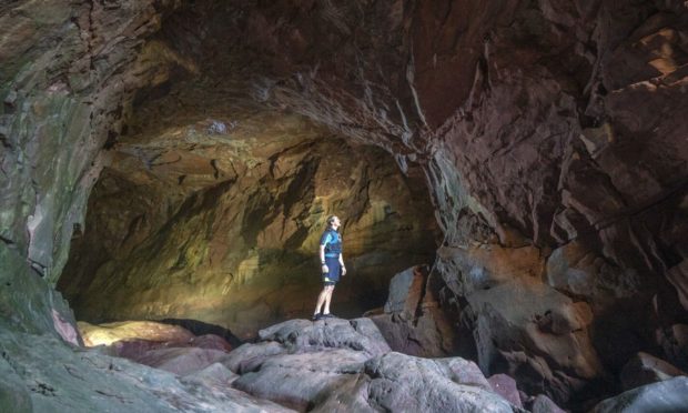 Cameron Smith, from Arbroath, looks out from Smuggler's Cave, which lies under the Arbroath Cliffs on the Angus coast. PA Wire/Jane Barlow