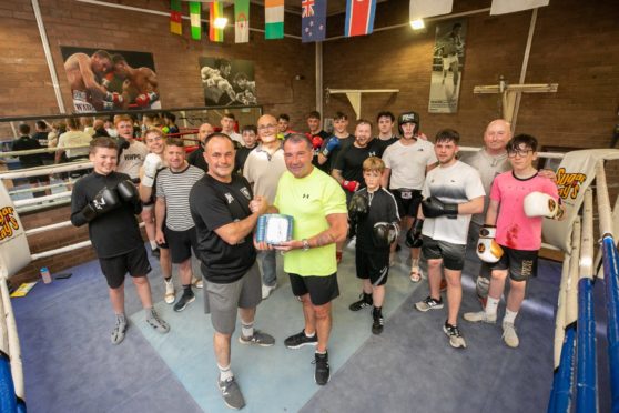 Gary Strachan hands over the defibrillator to  Lochee Boys Club.