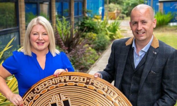 McGill's director of finance Sharon Craig and commercial director Douglas Smith holding the logo of cryptocurrency Bitcoin.