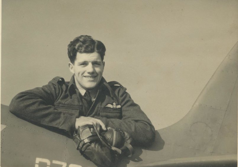 Sandy Gunn leaning on a spitfire aircraft.